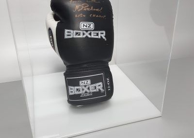 Clear acrylic disply cube with white base, housing a signed boxing glove