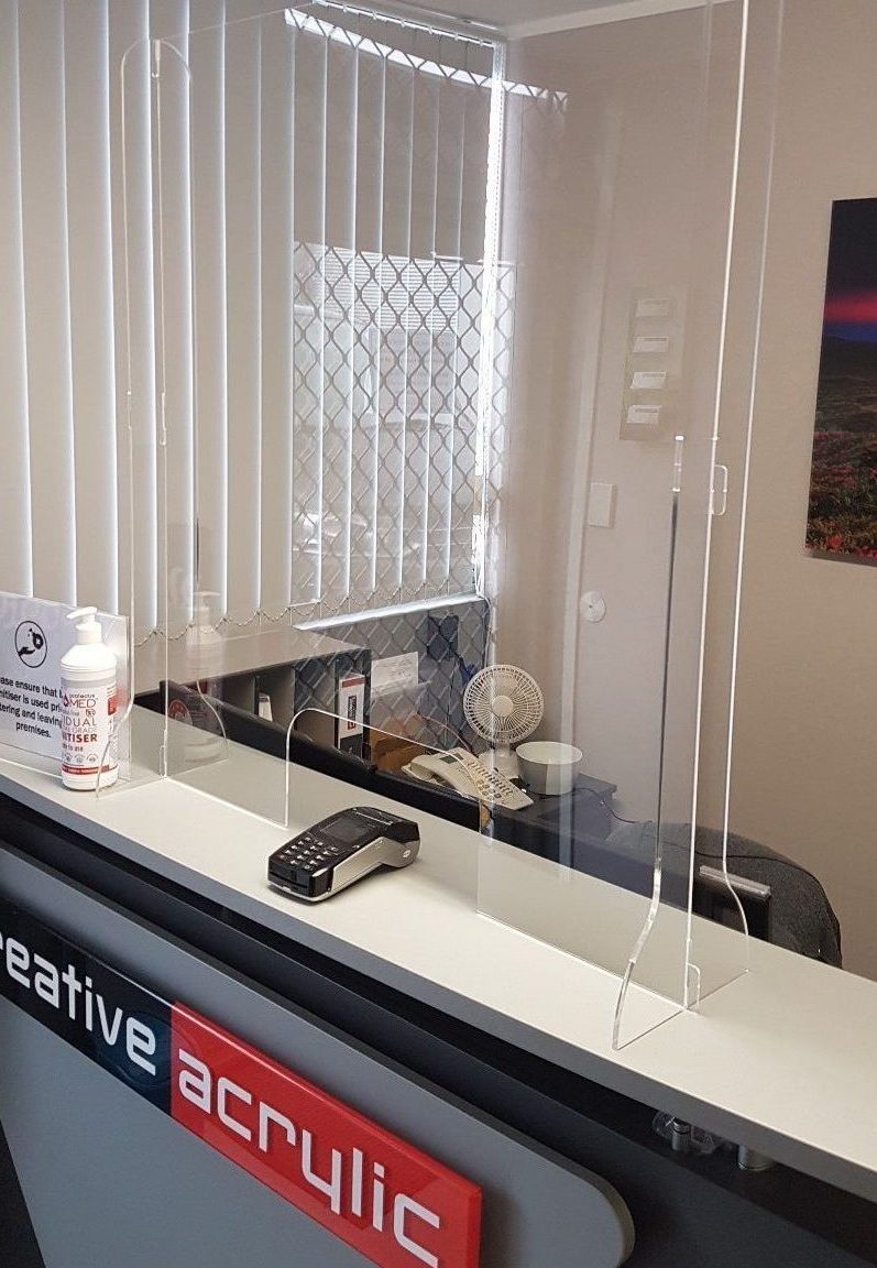 Clear acrylic sneezed guard shown on reception counter, with cut out for eftpos terminal.