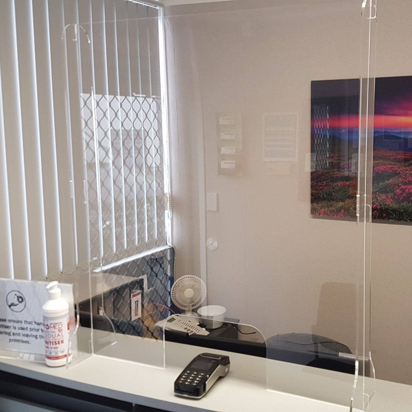 Clear acrylic sneezed guard shown on reception counter, with cut out for eftpos terminal.