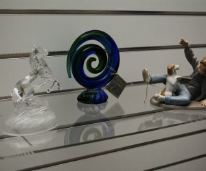 Clear acrylic slatwall flat shelf displaying a range of art pieces