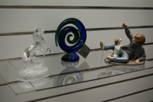 Clear acrylic slatwall flat shelf displaying a range of art pieces
