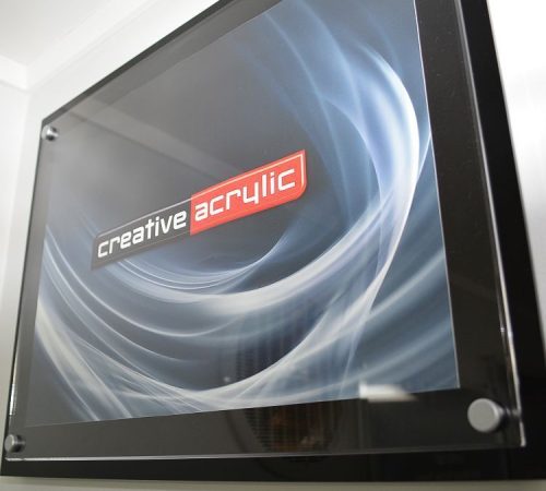 Custom made acrylic poster trap using a clear acrylic panel and a black acrylic panel and satin sign mounts attached to the wall