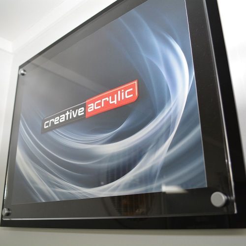 Custom made acrylic poster trap using a clear acrylic panel and a black acrylic panel and satin sign mounts attached to the wall