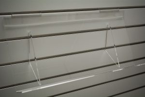 Clear acrylic slatwall tilt shelf, empty