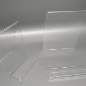 Clear acrylic universal display stand designed to hold a variety of items such as books, confectionary, and cosmetics.