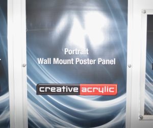 Wall mounted poster trap in clear acrylic, mounted with sign mounts and displaying an image.