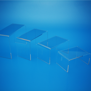 A set of 4 clear acrylic risers in a range of sizes, displayed on a blue background