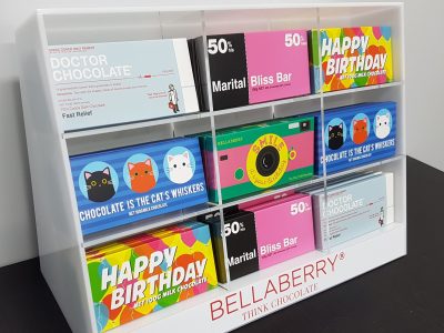 White acrylic point of sale display unit with clear acrylic dividers housing blocks of chocolate.