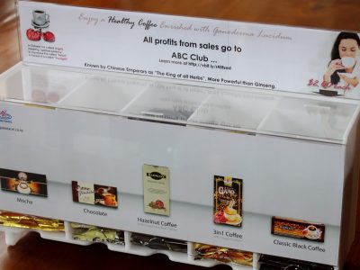 Opal acrylic gravity fed dispensing unit housing coffee sachets with a coin donation section.