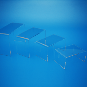 A set of 4 clear acrylic risers in a range of sizes, displayed on a blue background